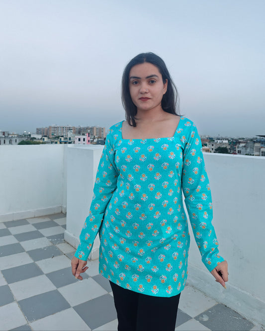 Woman wearing a turquoise floral dress on a rooftop with a cityscape in the background