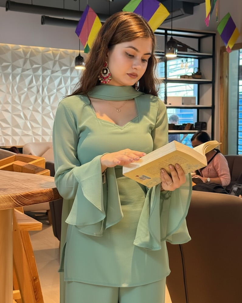 Woman in a light green outfit reading a book in a modern cafe.