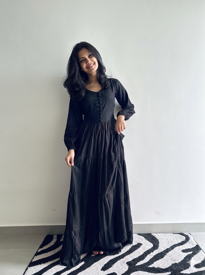 Black full sleeve tiered maxi dress for women in soft flowy rayon, showing covered buttons and flared tiered skirt – Vastramaniaa