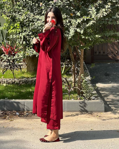 Woman in a red dress standing outdoors with greenery in the background