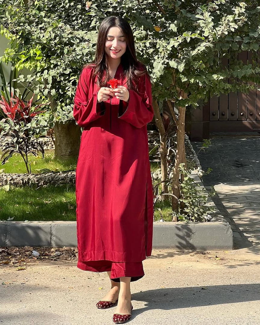 Woman in a red dress standing outdoors with greenery in the background