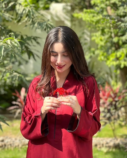 Woman in a red outfit holding a red flower in a garden setting