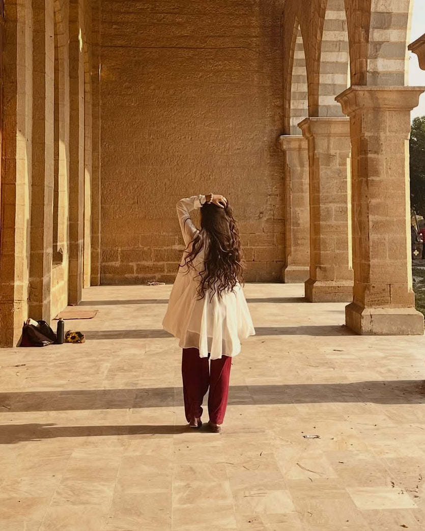 Woman walking through a large, open architectural space with columns and arches.