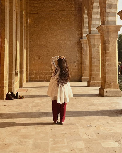 Woman walking through a large, open architectural space with columns and arches.