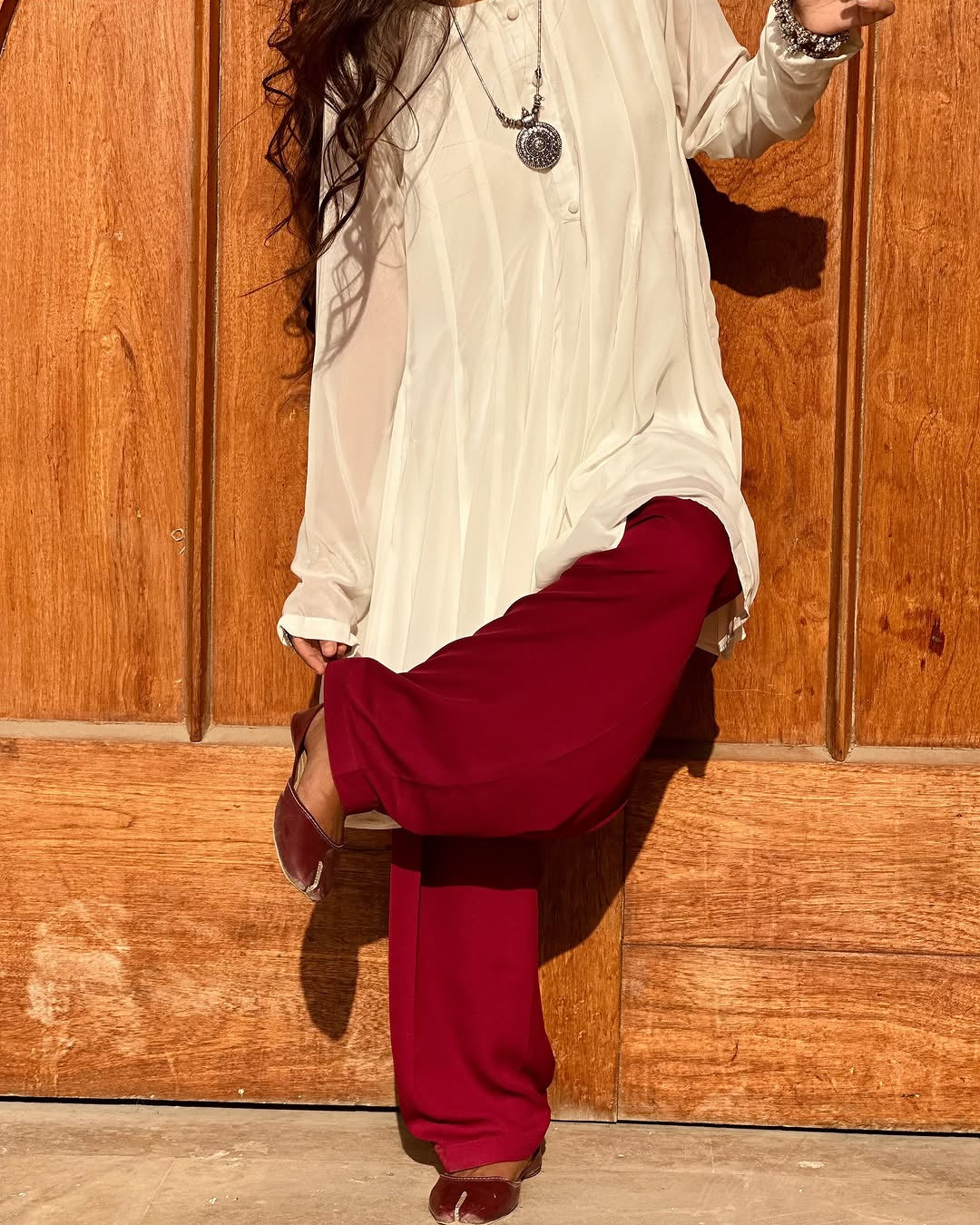 Person wearing a white top and red pants against a wooden background