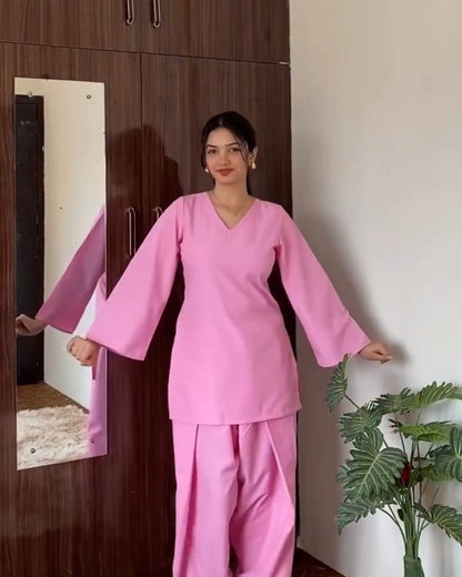 Person wearing a pink outfit standing in front of a wooden wardrobe.