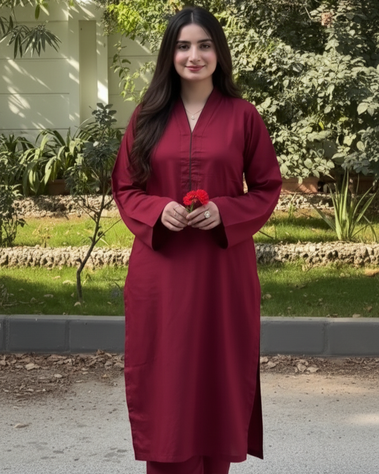 Woman in a red traditional outfit standing outdoors with greenery in the background