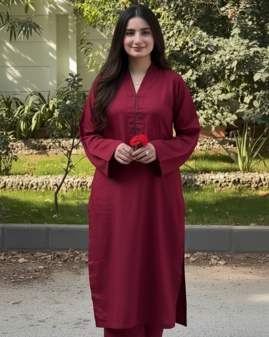 Woman in a red traditional outfit standing outdoors with greenery in the background
