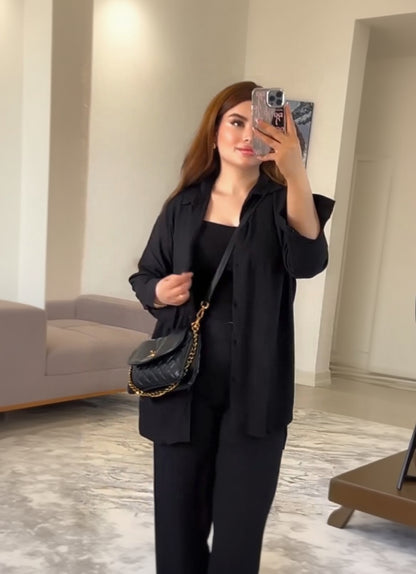 Person wearing a black outfit with a black handbag indoors.