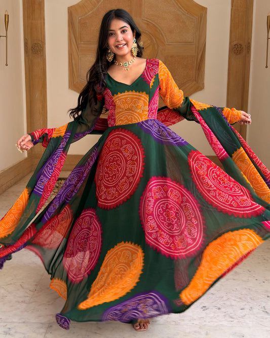 A woman wearing a vibrant, multicolored traditional Indian dress with a dark green base and large paisley patterns in orange, pink, and purple, captured in a full twirl pose.
