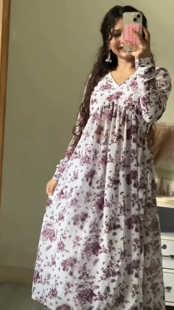 Woman wearing a white dress with purple floral patterns, taking a mirror selfie.
