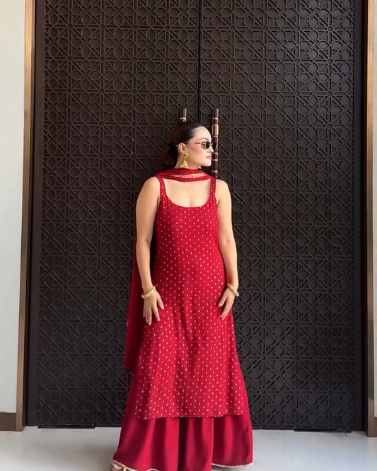 Woman in a red dress standing against a textured black wall.