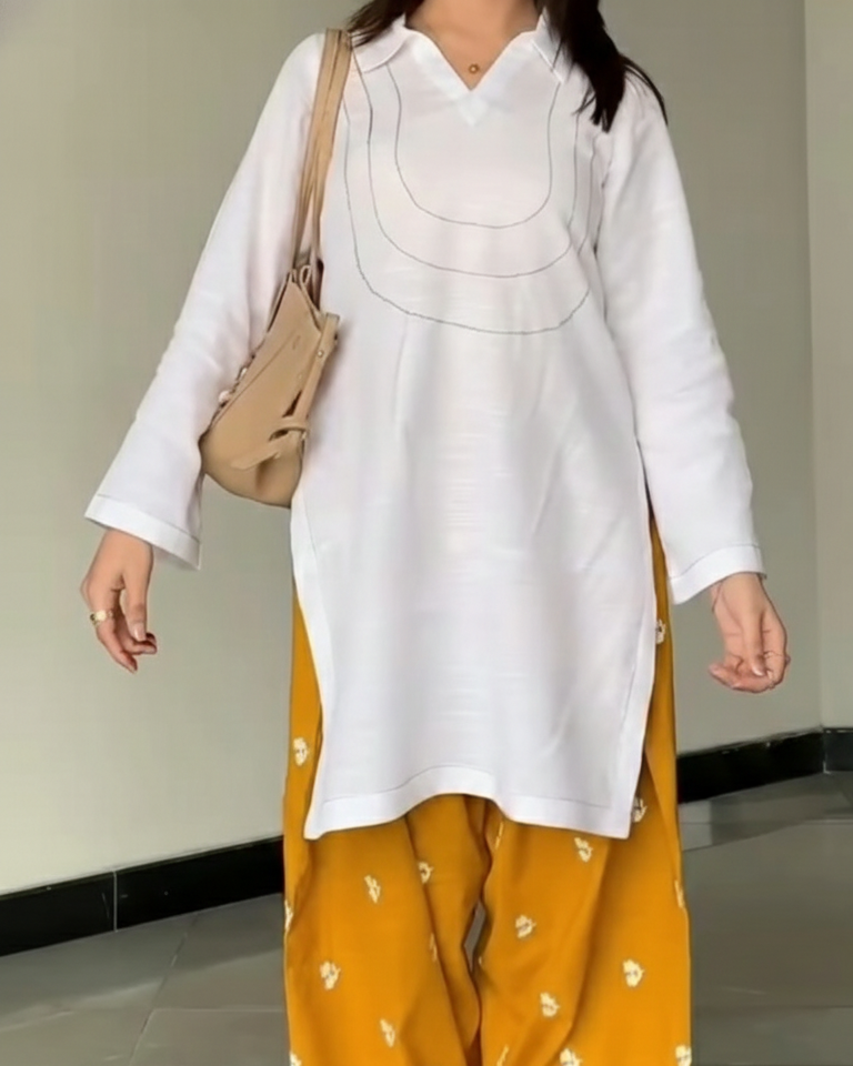 Person wearing a white top and mustard yellow pants with a beige bag.